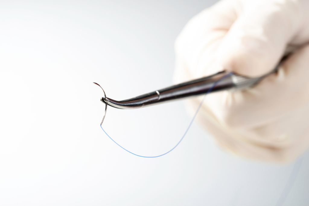 closeup of suture being held in a pair of pliers