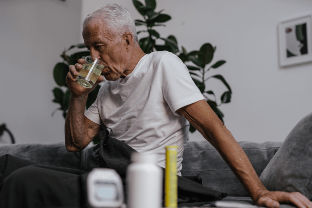 Sick elderly man drinking water in bed